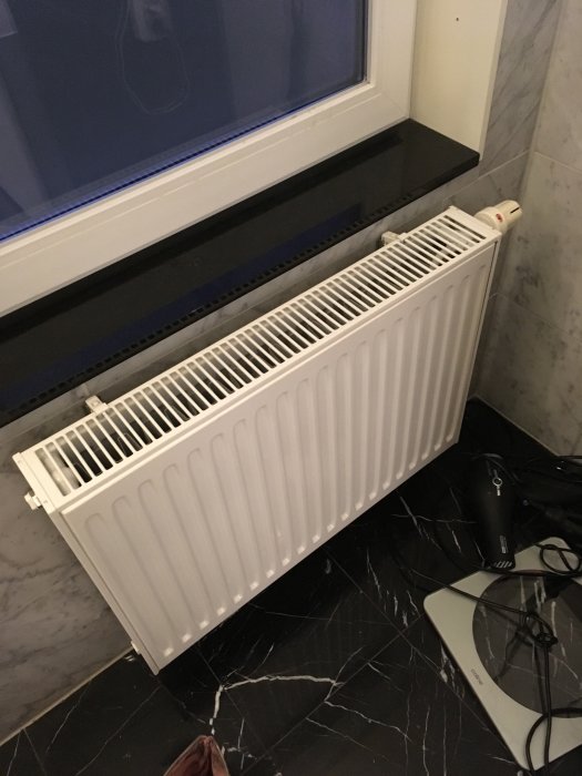 Radiator intill ett fönster och mörkt marmorgolv med en router och kablar, söker hjälp med installationsmetoder.