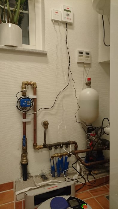 VVS-system med en monterad Waterfuse vattenfelsbrytare och synliga kablar längs väggen.