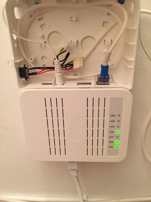 Router med ansluten LAN-kabel till LAN1 port och ledig WAN/EXT1 port, monterad på vägg.