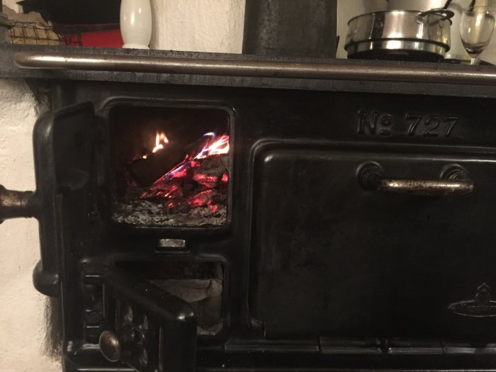 Gammal vedspis med eld i brännkammaren, används för att röka mat.