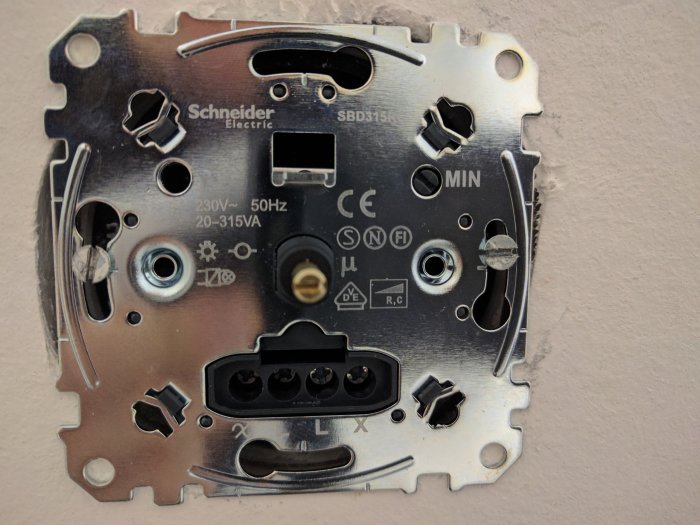Väggmonterad Schneider-dimmer utan täcklock, med plastmuttern och lösa kablar synliga.
