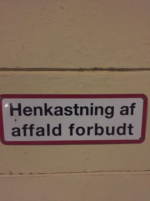 Skylt på vägg med texten "Henkastning af affald forbudt" vilket betyder "Slängning av skräp förbjudet" på danska.