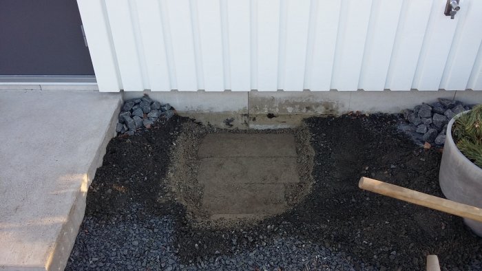 Uppgrävd mark vid husvägg visar mörka fläckar på kantelement som kan vara mögel.
