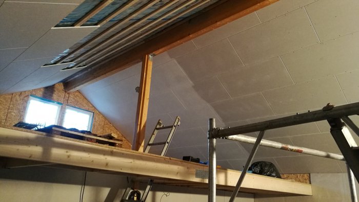 Pågående gipsväggsinstallation i ett vindsrum med synliga reglar och arbetsställning.