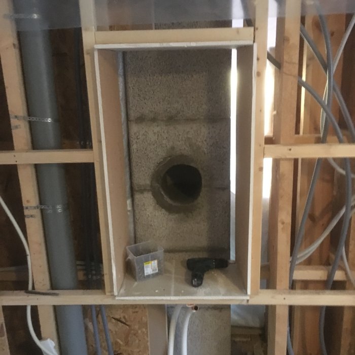 Gipslåda under konstruktion framför murstock med urtag för rökrör, träreglar och verktyg syns.