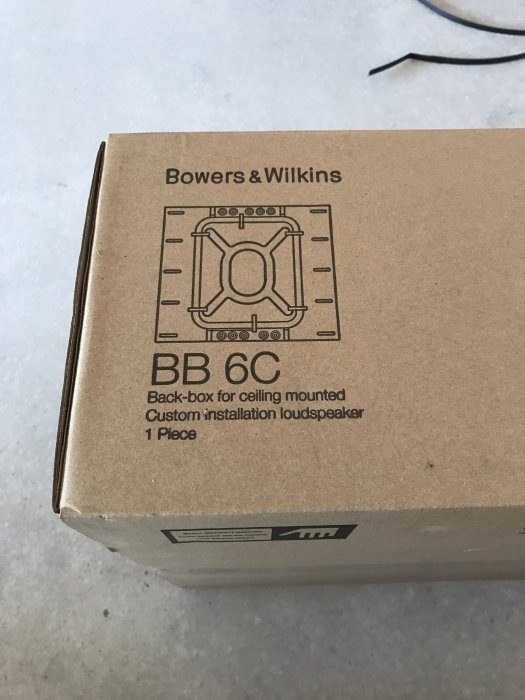 Kartong med Bowers & Wilkins back-box för infällda takhögtalare, BB 6C, på ett golv.