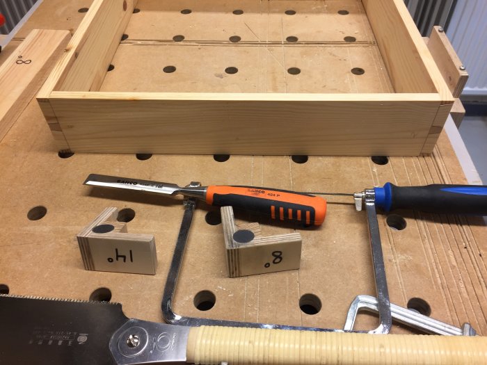 Träbitar och verktyg på arbetsbord, förberedelse för hopsättning av låda.