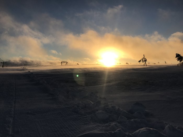 Solnedgång över ett snöigt landskap med dimma och skidliftar i Tandådalen.