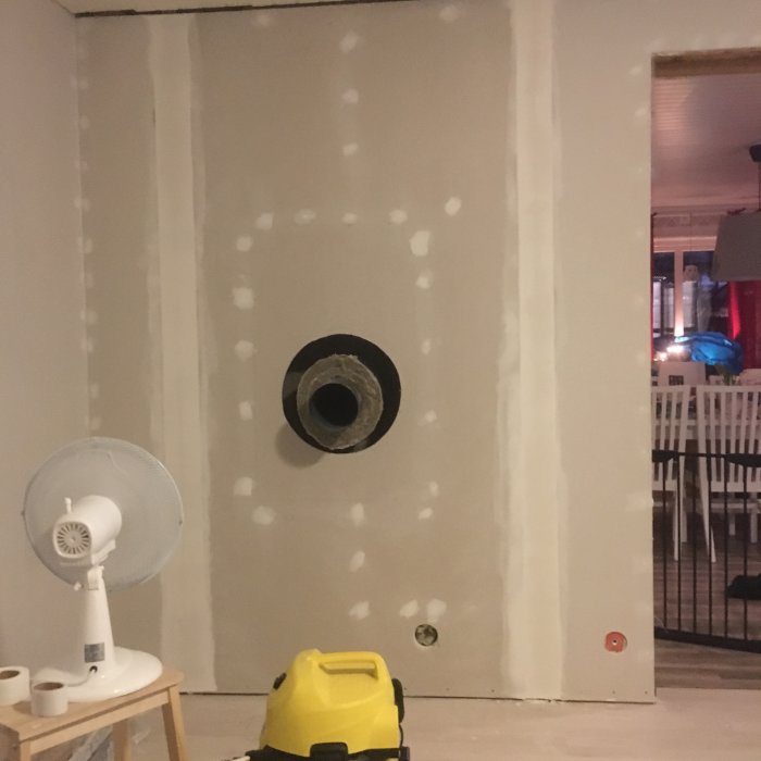 Vägg med spacklade skarvar och prickar redo för tapetsering, med synlig tilluftsventil och byggmaterial.