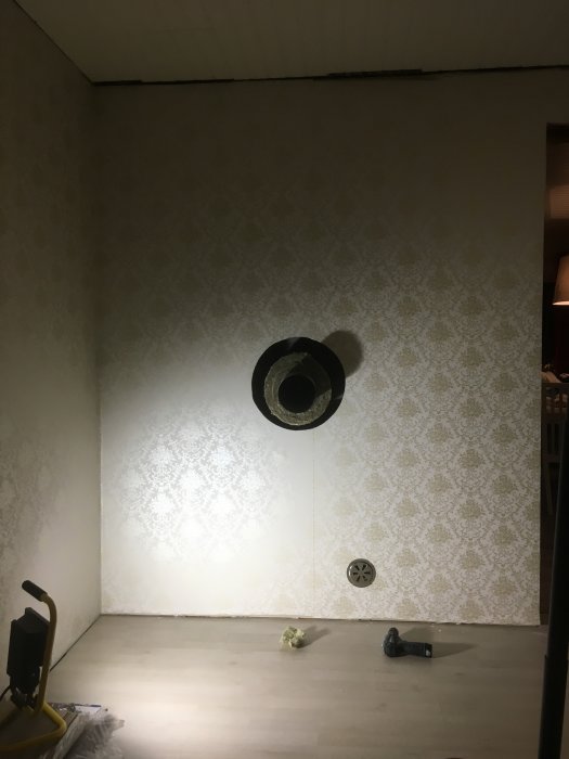 Renoverat rum med nytapetserade väggar och tilluftsventil installerad för kamin.