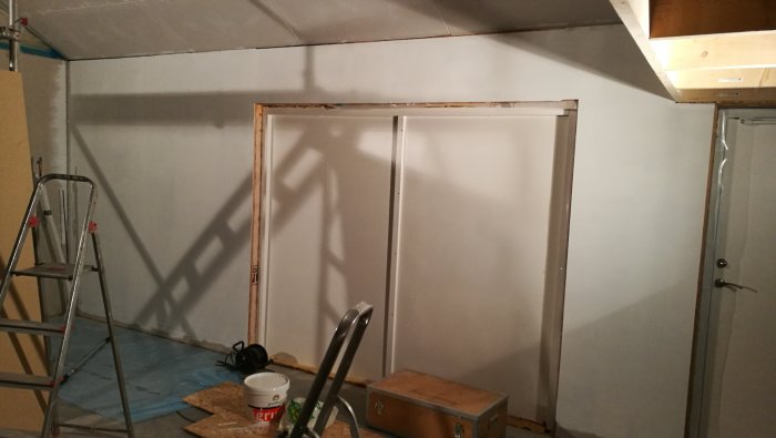 Nästan färdigspacklade väggar och tak i garage, med stege och verktygslåda synliga.