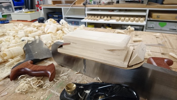 Hemmagjord slipkloss av furu med klämsågade kilarna på ett verktygsbord fullt av träspån.