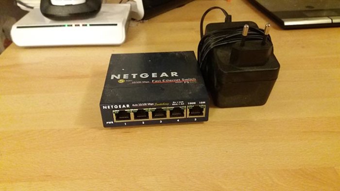 En äldre Netgear-switch och dess strömadapter på ett bord, indikerar ett nätverksproblem som beskrivits i inlägget.