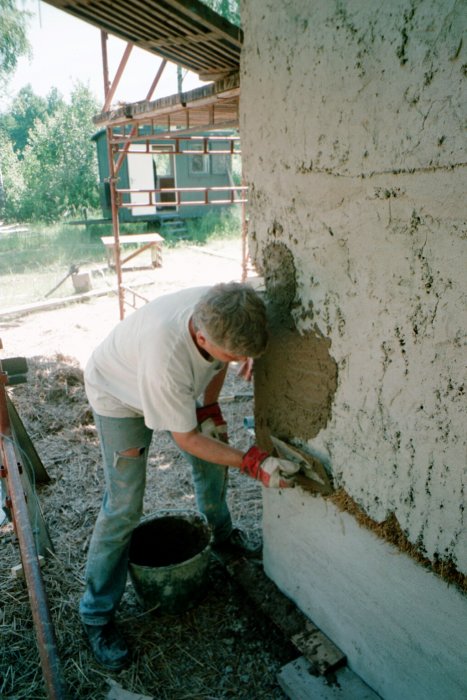 Person applicerar puts på en vägg utomhus, byggarbete i Växjö 1999.