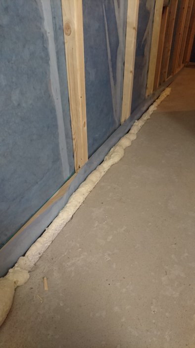 Foam insulation applied along the bottom of a wall where it meets the floor for sealing purposes.