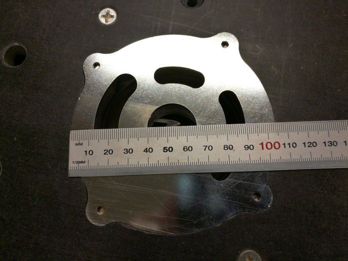 Måttstock ligger på en metall iläggsring för verktyg, som mäter 105mm i diameter.