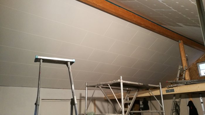 Nymålat tak med diagonala linjer och stegar i ett pågående byggprojekt.