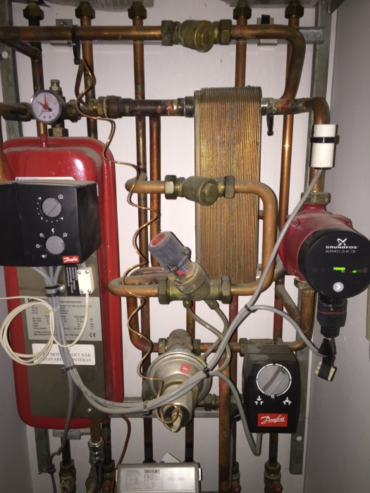 Fjärrvärmesystem med Grundfos Alpha2 pump, rör, mätare och reglage, med tecken på användning.