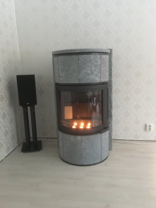 Kakelugn med eldtest innan plåtinstallation, saknar bakplåt, tända lågor synliga.