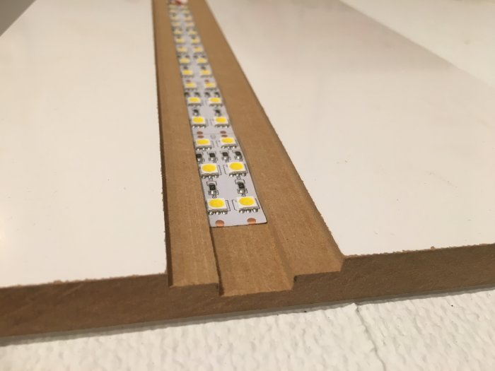 Dubbelradig LED-list monterad i ett fräst spår i trä med plats för opalvit plexiglas ovanpå.