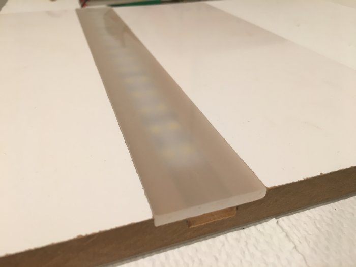 LED-list i fräst spår med ovanliggande opalvit plexiglasremsa på träyta.