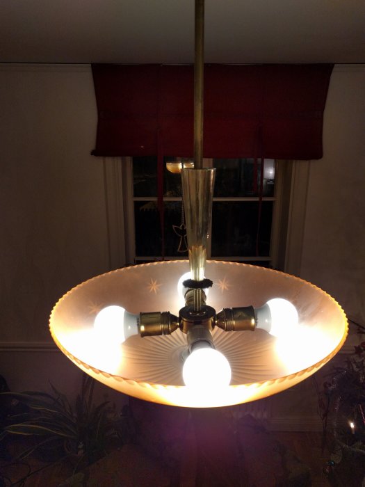 Taklampa med upphängning och skärm, nedifrån, visa tre tända ljuskällor och en snart färdig installation.