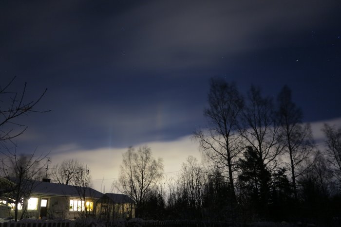 Nattvy med moln och månljus över hus och träd, med stjärnkonstellationen Orion synlig.