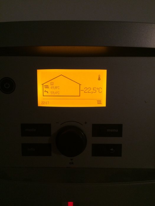 Upplyst display på en värmepanna som visar inomhus- och utomhustemperatur på 59,9°C respektive -22,5°C.