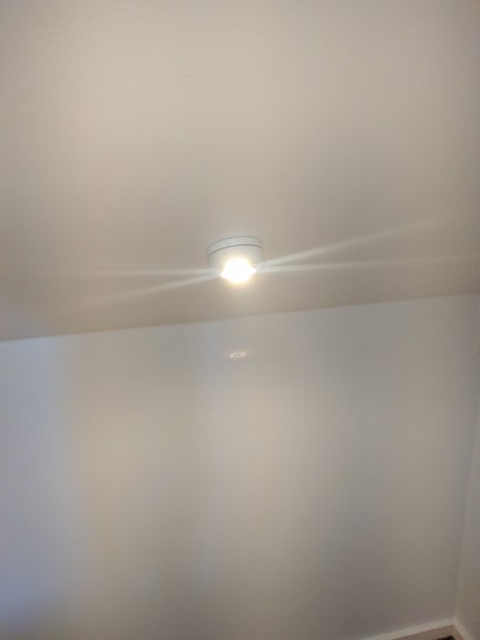 Nyinstallerad taklampa med tänd glödlampa på vit takyta bekräftar framgång med användning av clips.