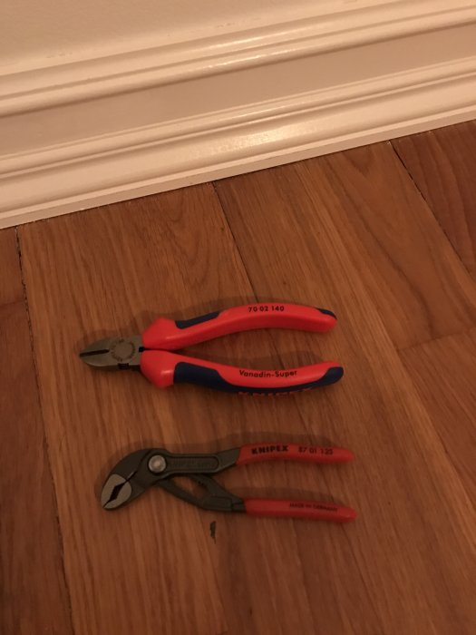 Två par tänger på trägolv, en sidavbitare och en KNIPEX Cobra vattenpumpstång.