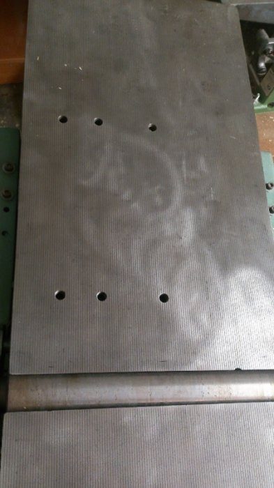 Inmatningsbord på en hyvelmaskin med borrade och gängade hål för montering av ett anhåll.