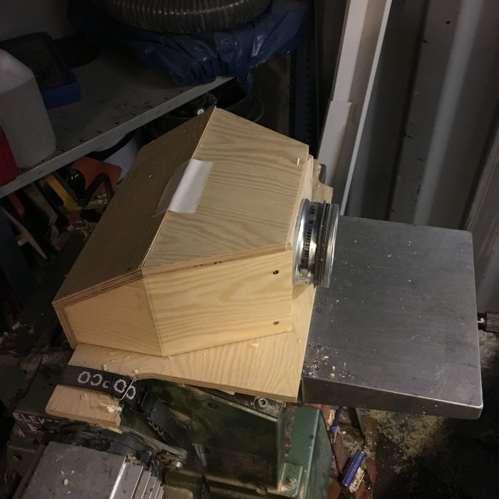 Hemmagjord träkonstruktion av 12mm plywood med en 100mm anslutning, placerad i ett rörigt garage.