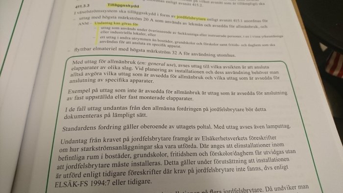 Uppslagen bok med text om elinstallation och jordfelsbrytare, markerad med grönt och gulmarkeringspenna.