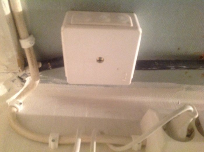 Vit skarvningsdosa på vägg med in- och utgående elkablar, som en del av bostadens elinstallation.