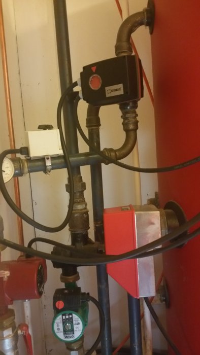 VVS-installation med röda och svarta rör, cirkulationspump från Wilo och Esbe komponent.