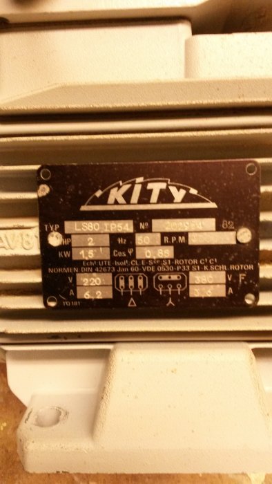Slitna märkplåten på en vit maskin, möjligen en motor, med namnet 'KITY' och tekniska specifikationer.