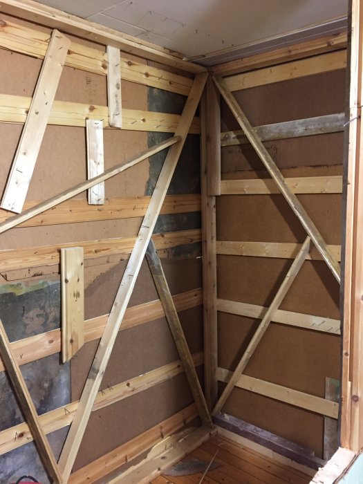 Träkonstruktion av tillfällig innervägg byggd med spikpistol och rivningsvirke.