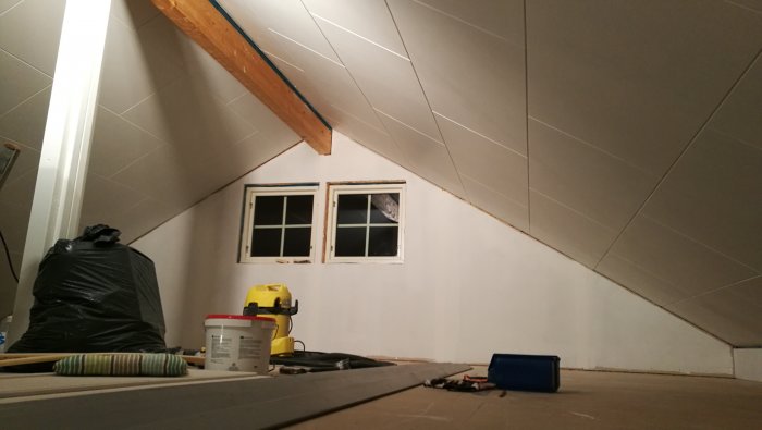 Nyinstallerade gipsskivor i ett verkstadsrum med sluttande tak och ett fönster.