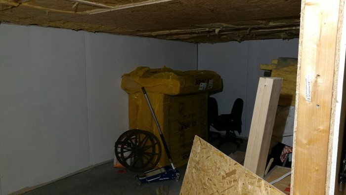 Ett verkstadsrum med nyligen monterade gipsskivor på väggen och isolerade loftgavlar, redo för besiktning.