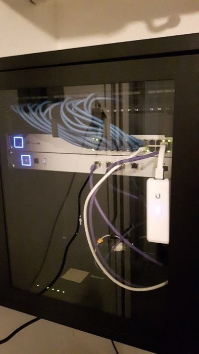 Nätverksskåp med Ubiquiti CloudKey och patchpanel med ethernet-kablar.