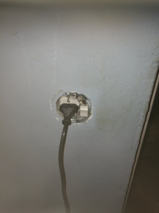 Trasigt eluttag med kombinerad lampknapp på vägg med inkopplad sladd.