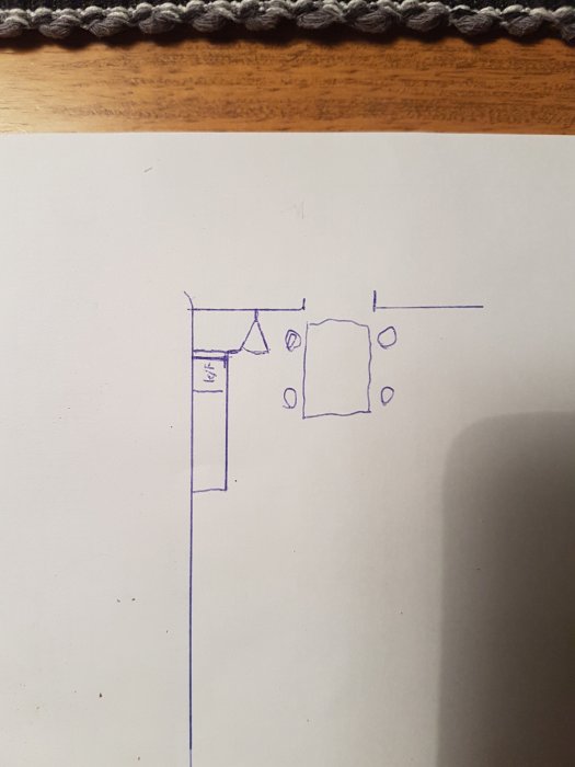 Handritad skiss av kökslayout med markerade mått och en snedning nära kylskåpet.