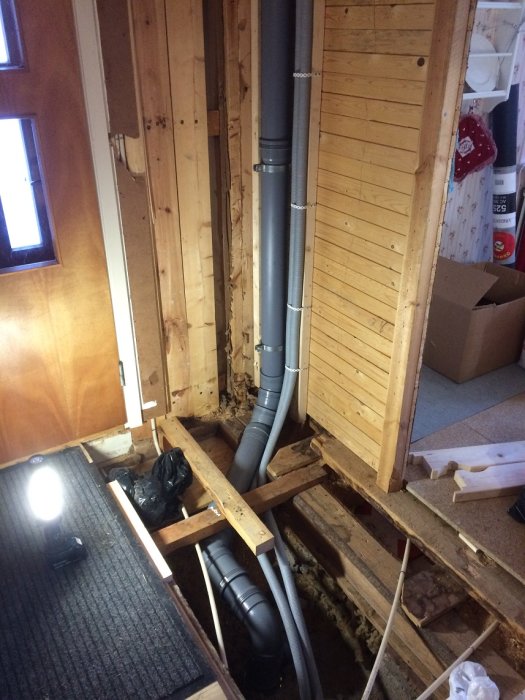 Installation av nytt avloppsrör i en källare, med rör och kopplingar synliga längs väggen och golvet.