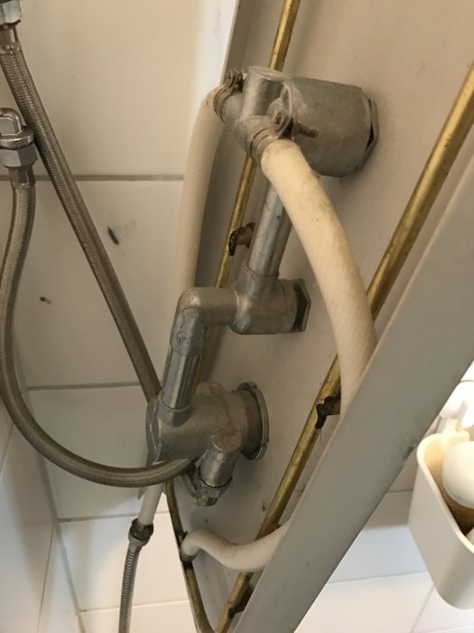 Duschpanelens baksida med synligt rör och reglage som antyds vara orsaken till läckage, i behov av underhåll.