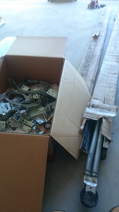 Överblivna garageportdelar med skenor, hjul, gångjärn, wire och skruvar, markerade för storlek 2500x2125.