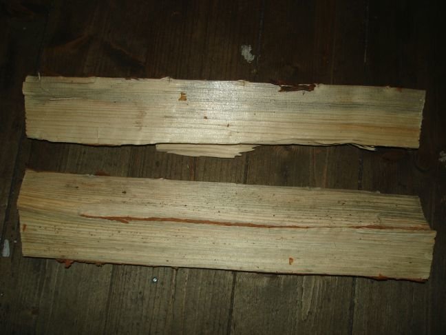 Två vedklabbar på trägolv med tecken på missfärgning eller mögel.