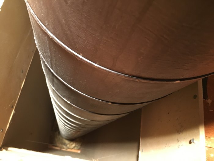 Metalliskt rör för en tidigare braskamin som går genom undertaket, i en källare som ska göras om till sovrum.