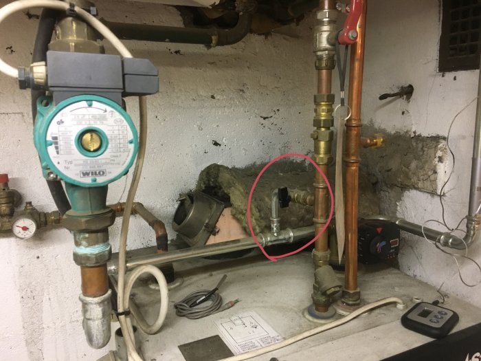 Värmesystem med cirkulationspump, kopparledningar och shunt markerad med röd ring.