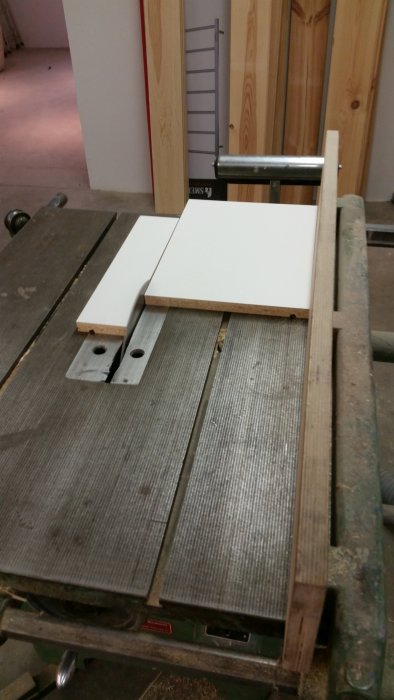 Sågad hyllpanel i MDF-material ligger på en slipningsmaskin i en verkstad, förberedd för montering.