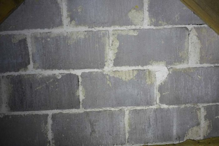 Vindsvåning med synligt mögel på gråa lättbetongväggar.